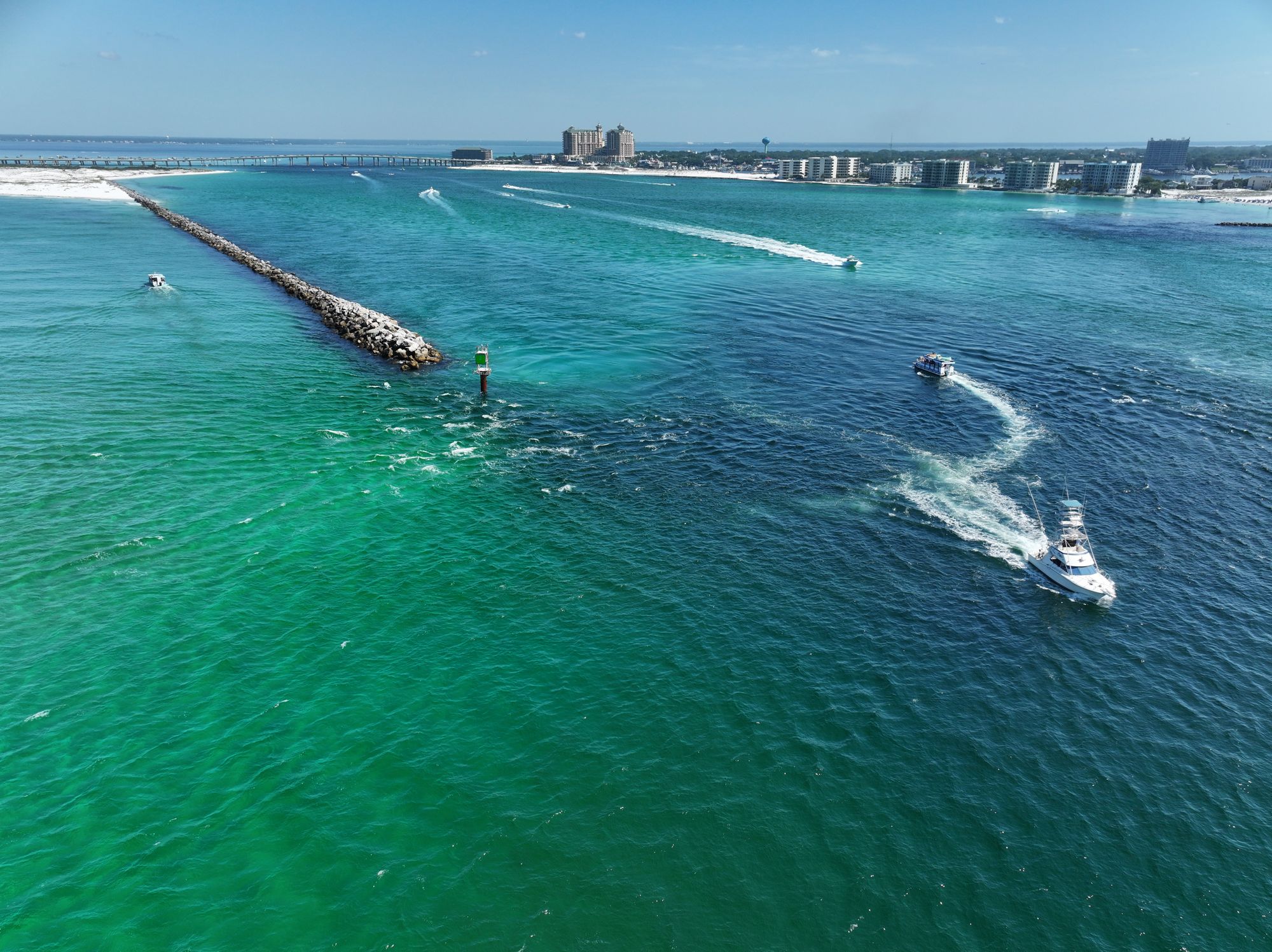 Aerial view of boats running out of East Pass into emerald water off Destin