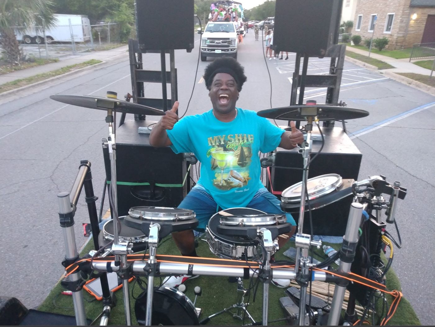 Robert grinning behind an electronic drum kit at an outdoor event