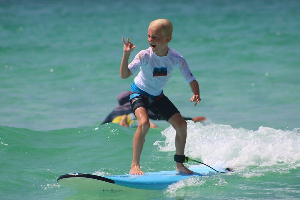 A young surfer standing on a blue soft-top board